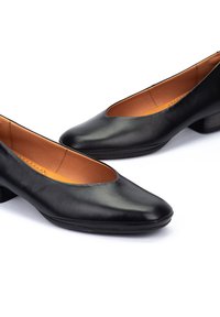 Pompes en cuir noir avec un bout arrondi et un petit talon carré. Texture lisse avec une large ouverture et des détails cousus le long des bords.