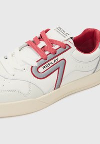 Weiße Sneaker mit rosa und roten Schnürsenkeln sowie grauen Akzenten. Ausgestattet mit strukturiertem Leder, einem gepolsterten Schaft und einem auffälligen "REPLAY"-Logo an der Seite.