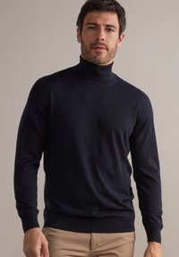 Maglione a collo alto blu navy con maniche lunghe, realizzato in un materiale morbido, presenta una silhouette aderente e polsini a coste per una vestibilità confortevole.