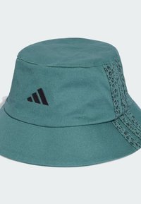 Tyrkysový klobúk s okrajom a čiernym logom Adidas, s leopardím vzorom na boku a textúrovaným dizajnom látky.