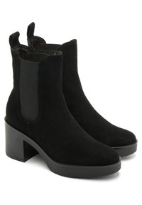 Botas negras de ante hasta el tobillo con un alto tacón de bloque, paneles laterales elásticos y un diseño de punta redondeada. Superficies texturizadas y forma aerodinámica.