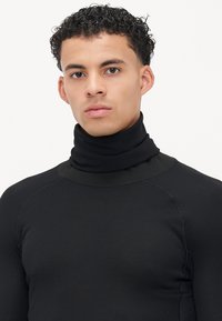 Sort turtleneck sweater lavet af ribbet stof. Har en tætsiddende design med en høj krave og raglan sømme for øget komfort.