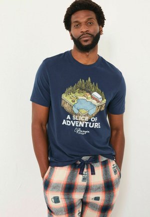 Marineblaues T-Shirt mit einem Grafikdesign von Naturlandschaft. Beiger karierter Hausanzug mit bedruckten Tassen. Beide sind lässig und bequem.