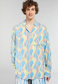 Camicia a bottoni a motivi in verde chiaro, blu e rosa; presenta disegni fluidi e ondulati e una tasca sul petto; realizzata in un tessuto leggero.