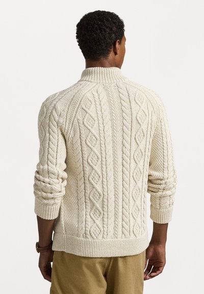 Suéter de malha em creme com gola alta, apresentando padrões em diamante e canelados, e mangas texturizadas. Ajuste casual com bainha canelada.