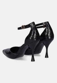 Zapatos de tacón alto negros con punta afilada, textura de cocodrilo y correa de tobillo ajustable. Presentan un tacón delgado y un acabado suave.