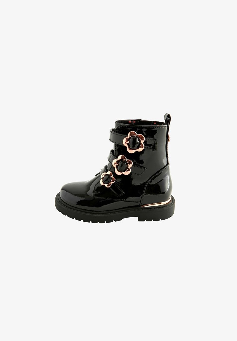 Schwarze Lackleder-Stiefelette mit floralen Akzenten, verstellbaren Riemen und einer strukturierten schwarzen Sohle. Enthält einen metallisch goldenen Streifen nahe der Basis.