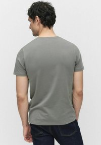 Grå kortærmet t-shirt lavet af bomuld. Glat tekstur med rund hals og tætsiddende design. Bagfra viser den enkelhed og rene linjer.