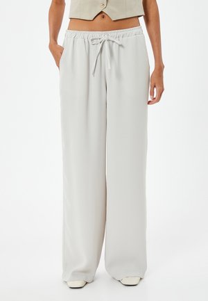 Pantalon large gris clair en tissu lisse, avec une taille élastique et un cordon de serrage, ainsi que des poches latérales.