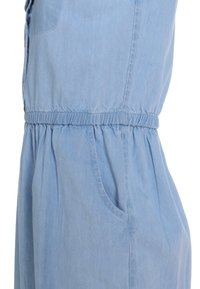 Robe en chambray bleu avec une taille froncée, des poches latérales et une coupe décontractée. Présente une texture douce et un tissu léger pour le confort.