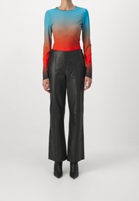 Maglietta a maniche lunghe con gradiente che passa dal blu al rosso, abbinata a pantaloni in pelle neri a vita alta e stivaletti neri a punta.