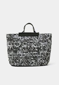 Sac cabas en paille tressée avec un motif noir et blanc, doté d'une lanière supérieure en cuir noir lisse et d'une structure robuste.