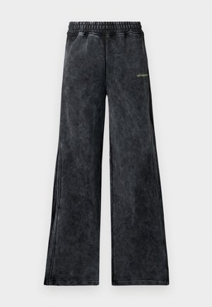 Wijd-uitlopende broek van een gestructureerde zwarte stof met een subtiele glans. Bevat een elastische tailleband en een klein groen logoaccent aan de voorkant.