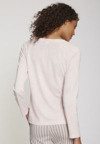 Helles rosa Langarmoberteil mit Rundhalsausschnitt und einer weichen, glatten Textur, kombiniert mit gestreiften Pyjamahosen.