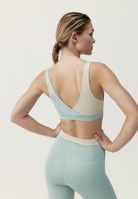 Lättvikts sportbh i tvåfärgad design, med en beige och mintgrön färgskala, en bred rem - och en slät textur.