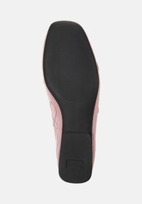 Zapato de tela rosa con superficie texturizada, que cuenta con una suela de goma negra sólida y un tacón cuadrado para mayor estabilidad.