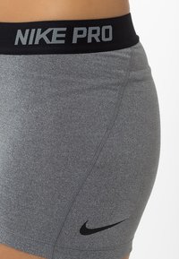 Szare sportowe szorty Nike Pro z czarnym paskiem i małym czarnym logo Nike swoosh na lewej stronie ud. 