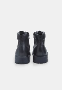 Stivaletti neri in pelle con punta tonda, suola in gomma piatta e chiusure a zip su entrambi i lati. Presentano una linguetta sul retro.