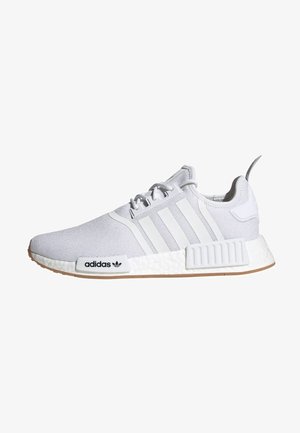 Zapatilla blanca Adidas NMD con parte superior de punto texturizado, tres rayas en el lateral, detalle de la entresuela con marca y suela de goma natural.