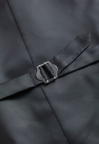 Mørkegråt stof med et matchende bælte, der har en sølvfarvet rektangulær spænde med afrundede, stiliserede kanter.