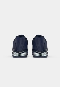 Granatowe buty do biegania z teksturowaną cholewką, odblaskowymi akcentami i zaprojektowaną odciążoną podeszwą. Charakteryzują się zaokrąglonym obcasem dla zwiększenia stabilności.