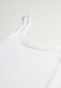 Witte katoenen tanktop met dunne bandjes, met een gladde textuur en een ronde halslijn. De stiksels zijn zichtbaar langs de naden.