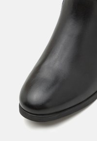 Black leather ankle boot with a smooth, shiny texture, rounded toe, and flat sole. No visible hardware or patterns.