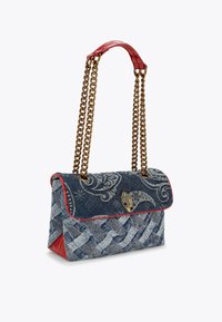 Borsa in denim con motivo intrecciato, dettagli rossi, tracolla in catena dorata e chiusura decorativa. Presenta un design intricato sul risvolto.