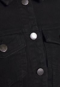 Mustat farkkutakki, jossa on hopeiset napit ja kaiverrus "ONLY". Mukana rintataskut ja teksturoitu kangaspinta.