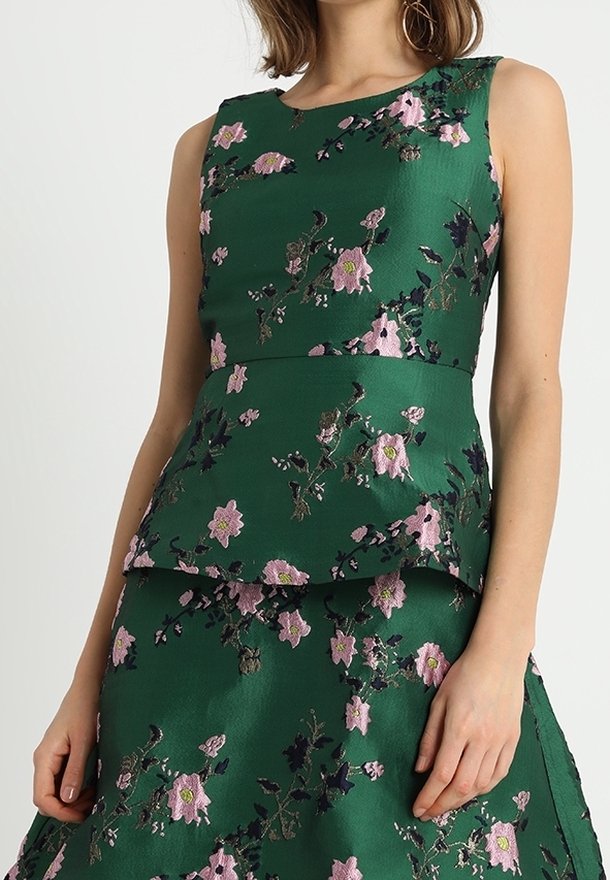 Robe fleurie verte avec un tissu texturé, design sans manches, et taille peplum superposée ornée de broderies roses et bleu foncé.