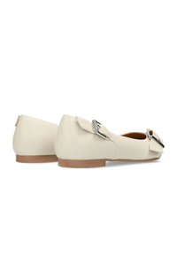 Cremefarbene Ballerinas aus Leder mit flacher Sohle, Schleifendetail und silbernen Beschlägen. Glatte Textur, abgerundete Spitze und minimalistisches Design.