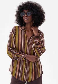 Striped button-up shirt in brown, green, and cream; features a collared neckline and long sleeves with buttoned cuffs and rounded hem.