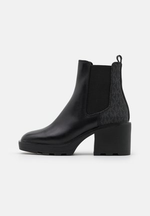 Bottine en cuir noir avec talon épais, panneau latéral élastique et détail en tissu texturé à l'arrière.