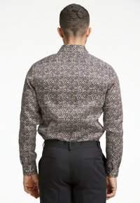 Camicia da uomo a maniche lunghe in tessuto con un motivo di piccoli cerchi marroni e neri su uno sfondo bianco. Presenta un colletto standard e polsini con bottoni.