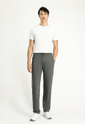 Graue, maßgeschneiderte Hose mit einem Kordelzugbund, geraden Beinen und einem subtilen strukturierten Muster, kombiniert mit einem schlichten weißen T-Shirt und weißen Sneakern.