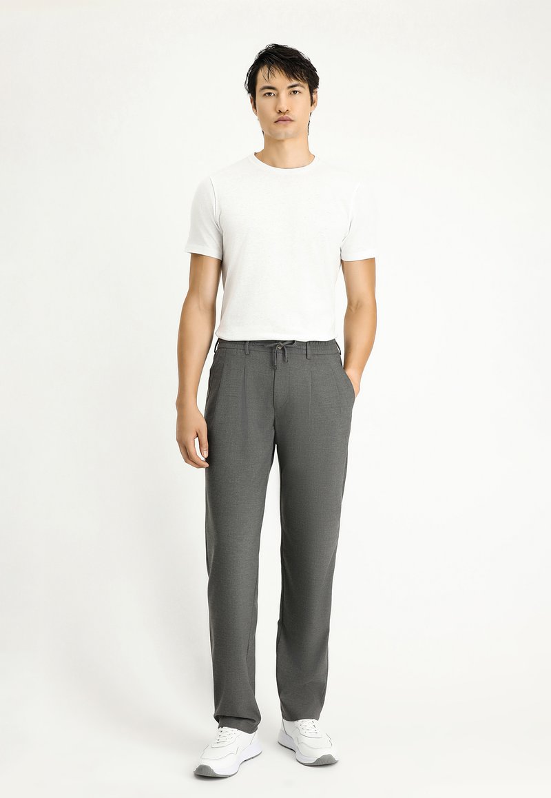 Pantaloni grigi su misura con vita regolabile, gamba dritta e un sottile motivo testurizzato, abbinati a una t-shirt bianca semplice e sneakers bianche.