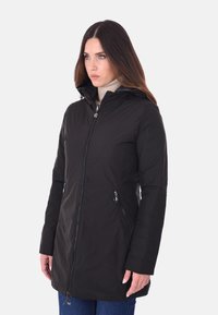 Cappotto imbottito nero con chiusura a zip, colletto alto e due tasche laterali. Tessuto morbido e design di lunghezza media per calore e copertura.