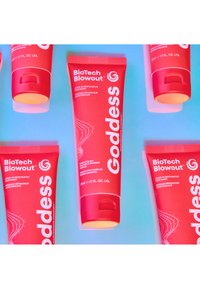 Røde klemmetuber med BioTech Blowout leave-in restituerende hårmaske, med hvit tekst og virvlende mønstre, mot en blå bakgrunn.