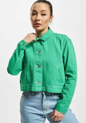 Chaqueta de mezclilla verde con cuello, botones frontales y dos bolsillos laterales. Cuenta con costuras blancas y mangas largas. Diseño casual y corto.