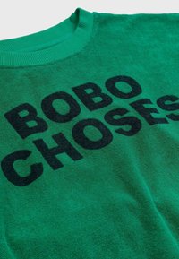 Sudadera verde de cuello redondo con el texto negro "BOBO CHOSES" impreso en la parte del pecho en letras mayúsculas y en negrita.