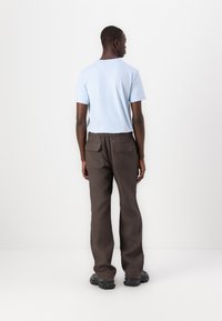 Lichtblauwe short-sleeve shirt, bruine wijde broek met achterzakken, en zwarte chunky schoenen. Glad materiaal met een minimalistisch design.