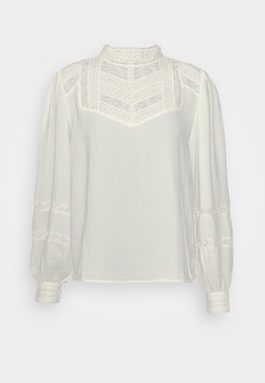 Hvid bluse med lange ærmer, blondepåskæring, høj hals og blonde detaljer på ærmer og skuldre.