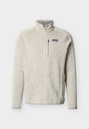 Ελαφρύ μπεζ μπουφάν φλις με πλήρη φερμουάρ, υψηλό γιακά, τσέπη στο στήθος με φερμουάρ, πλαϊνές τσέπες και το λογότυπο της Patagonia στο αριστερό στήθος.