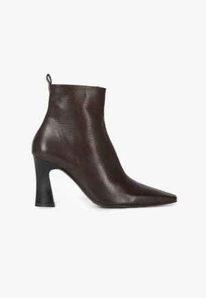Brauner Knöchelstiefel aus strukturiertem Leder mit spitzer Zehenpartie und einem geformten schwarzen Absatz. Hoch geschnittenes Design mit einer Schlaufe am hinteren Teil.