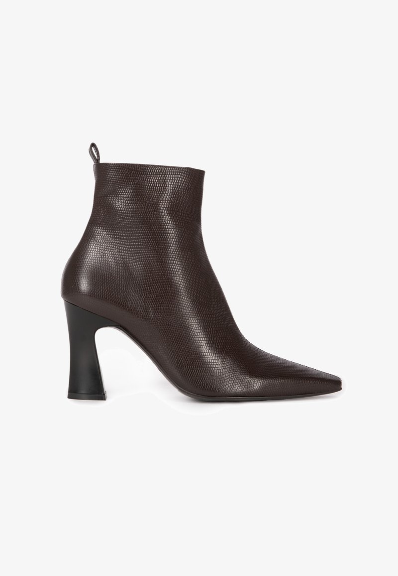 Brown ankle boot made of textured leather, featuring a pointed toe and a sculpted black heel. High cut design with a loop tab at the back.