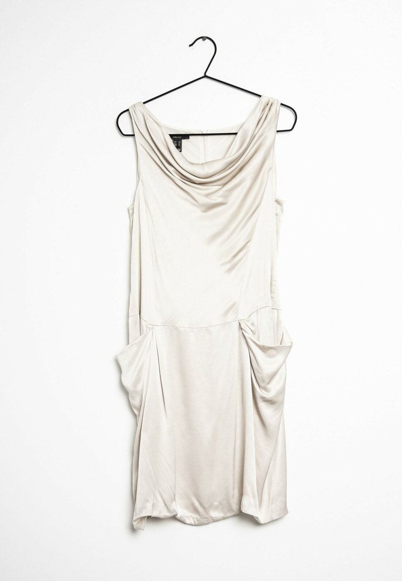 Robe sans manches beige en tissu lisse, dotée d'un col drapé et de deux poches latérales avec des détails froncés. Accrochée à un crochet noir.