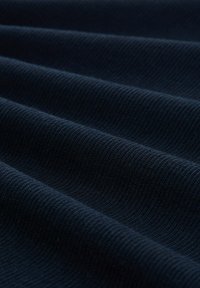Tessuto a maglia blu navy con una superficie testurizzata, caratterizzato da nervature e avvallamenti paralleli che creano una serie di morbide pieghe.