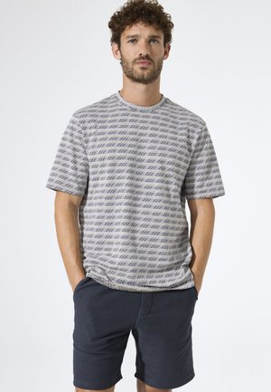 T-shirt met korte mouwen en ronde hals in lichtgrijs met donkerblauwe geometrische strepen. Gecombineerd met marineblauwe korte broek met een gestructureerde stof.