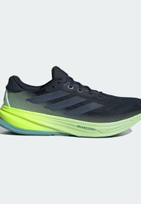Chaussure de course noire et grise avec une semelle vert vif étiquetée « DREAMSTRIKE+ » et trois bandes gris foncé sur le côté.