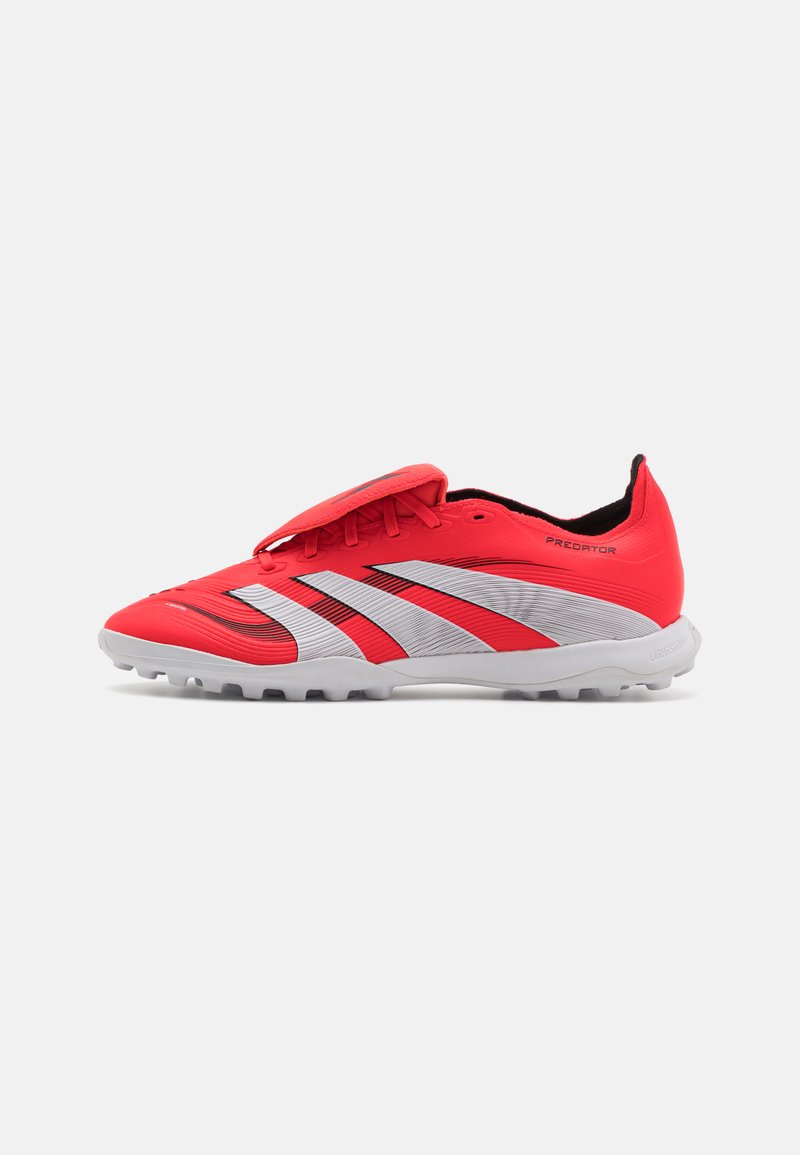 Red athletic shoes with a textured upper and adjustable strap. Features three white stripes and a grey outsole with cleats.